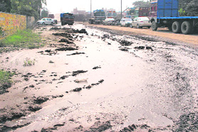 A Focal Point road with deep potholes, stagnant water and heaps of garbage. 