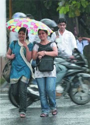 Girls enjoy rain from under an umbrella in New Delhi on Monday.