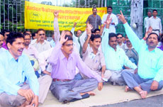 Ministerial staff stage a dharna at Gandhi Park in Dehradun on Monday.