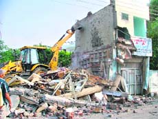 A JCB machine demolishes a shop in Ludhiana on Monday. 