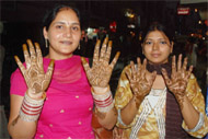 Women show the freshly-applied henna on their palms