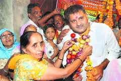 A woman supporter of Chander Prakash Kathuria, BJP candidate from the Karnal assembly constituency, offers him a garland of onions and tomatoes on Thursday.