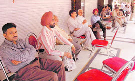 Income Tax officials wait outside the Kumar group of showrooms for conducting a raid in Sector 11, Chandigarh, on Friday.