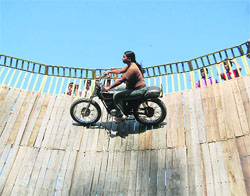 Neesha drives a motorcycle in a well of death at the ongoing Uttarakhand Trade Mahotsav in Dehradun on Sunday