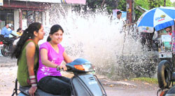 Two women pass by a burst water pipeline at Ranipur Chowk in Haridwar on Sunday. 