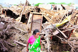 A flood victim searches her damaged home at Rajoli village in Mehboobnagar district of Andhra Pradesh.
