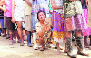 A woman squats while waiting for relief distribution in Rosales, north of Manila, Philippines, on Sunday. 