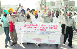 Traders and small-scale industrialists hold dharna in Ludhiana on Monday.