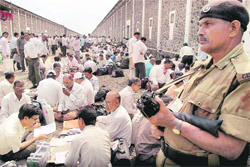A security man guards polling officials during the distribution of EVMs at Sangli 