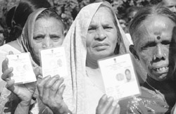 Residents show their I-cards, while waiting for their turn to cast votes for Haryana Assembly polls