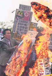 Anti-North Korea protesters burn portraits of North Korean leader Kim Jong-il and mock missiles at a protest denouncing the North's missile launch, in Seoul on Tuesday. The placard denounces the North Korean nuclear programme.