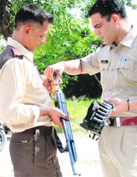 A police official examines the guards weapon that went off injuring two persons at Mohali
