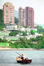 Upmarket apartments and houses rise behind a fisherman on his boat in Hong Kong's Deep Water Bay on Sunday.