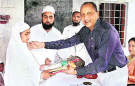 Dr Harinder Rawat, advisor to Uttarakhand Agriculture Minister, gives away study material to a student of Madrassa Anwarul-UIloom, Ajabpur Kalan, near Dehradun on Sunday.