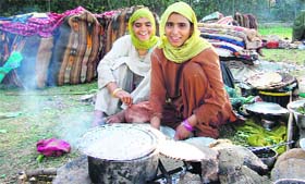 Two migrant women from Sarthal are all smile while preparing food by the roadside