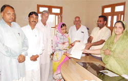 Rawatsar MC president Neelam Saharan (extreme right) giving away an ownership right letter to a housewife on Tuesday.