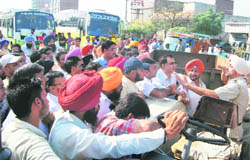 A police official pleads with protesting shopkeepers to disperse and remove the blockade from the national highway in Ludhiana on Tuesday.