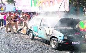 Fire fighters douse fire on a car at Ranipur Mor in Haridwar