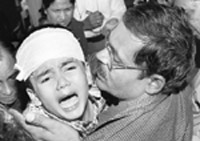 A passenge of the Mewar Express holds his injured kid after the express train arrives in New Delhi 