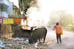Smoke billows out of a dustbin as MC safai karamcharis burn garbage inside it, flouting the ban on burning of garbage.