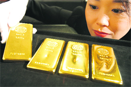 An employee poses with gold bars at the Ginza Tanaka store in Tokyo 