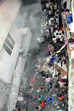 People try to help fire officials in dousing flames at a building in Field Ganj, Ludhiana, on Friday.