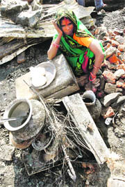 A slum-dweller sits amid the debris of her burnt shanty in Siliguri on Sunday. More than 1,000 persons were left homeless after a fire swept through a slum area. 
