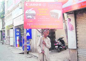 To earn a living, an old man walks on the street carrying an advertisement board