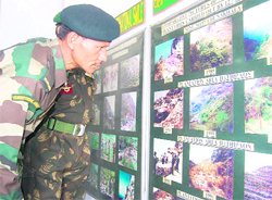 An Armyman takes a closer look at a photo exhibition put up by the 127th Eco Task Force in Dehradun on Monday.