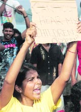 A woman, part of 260 Sri Lankan asylum seekers who were detained by the Indonesian Navy, holds a placard during a protest on a boat in Indonesia on Monday
