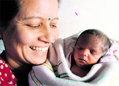 Sita is all smiles as she cuddles her adopted baby, who was abandoned soon after her birth, in Ludhiana on Tuesday.