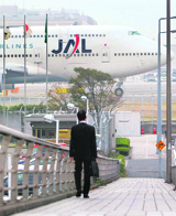 A man walks as a Japan Airlines (JAL) aircraft moves at Tokyo's Haneda airport