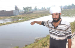 A villager shows the ponds, posing a grave danger, in Jamsher village. 