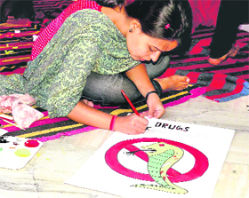 A girl makes a poster to raise awareness against drugs during a contest in Haridwar.