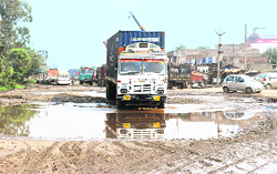 Water accumulated on a potholed road makes it difficult for vehicles to ply in the industrial area.