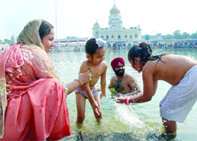 A Sikh family takes a holy dip at the Bangla Sahib Gurdwara on the occasion of 540th birth anniversary of Sri Guru Nanak Dev in New Delhi on Monday