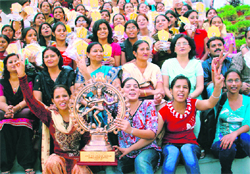 Students holding the overall championship trophy with the principal and other faculty members of the college.