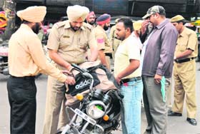 A cop checks the bag of a commuter in Ludhiana on Monday ahead of the Punjab bandh called by Sikh organisations