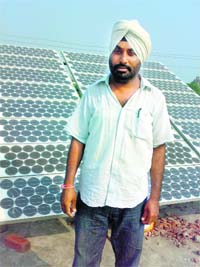 Ajmer Singh Gill, with photovoltaic panel that lies idle at his fields at Bhadewal village near Ahmedgarh