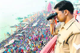 A policeman keeps a watch on devotees on the banks of the Ganga on the occasion of Kartik Purnima in Varanasi on Monday.
