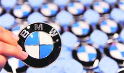 This file picture shows a worker holding up a logo of German carmaker BMW at the company's plant in the southern German city of Dingolfing. BMW joined compatriot Daimler on Tuesday in posting dismal third quarter figures and warned there was no guarantee a recovery is underway, though strong growth was seen in China.