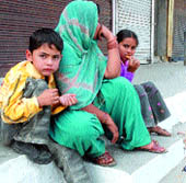 A woman along with children outside closed shops in a Jalandhar bazaar on Tuesday.