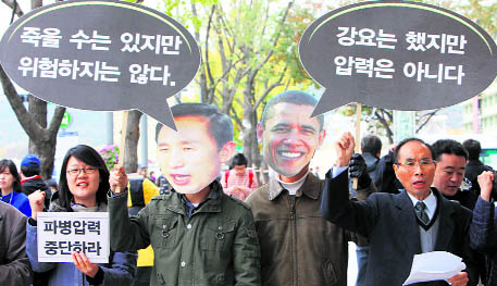 Protesters wearing masks of South Korean President Lee Myung-bak and US President Barack Obama shout slogans during a rally denouncing South Korean government's troop dispatch plan to Afghanistan, near the US embassy in Seoul on Tuesday. The black banners read, "(South Korean soldiers) could die but it's not dangerous" (left) and "I demanded (the dispatch of troops) but it's not a pressure".