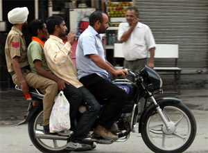 A policeman gets a ride on a motorbike as the fourth passenger in violation of traffic rules in the city. 