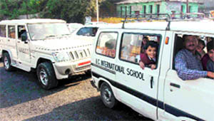 Schoolchildren wait for the opening of the road leading to the Congress Headquarters at the Circular Road in Jammu on Wednesday.