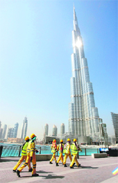 Workers walk past Burj Dubai, the world's tallest man-made structure under construction, in Dubai on Thursday. Former boomtown Dubai, home to man-made palm-shaped islands, is poised to catch international attention again with the inauguration of the world's tallest tower on January 4 in a move that could help revive the emirate's sluggish property market. The opening of 800-metre building, developed by real estate giant Emaar Properties, was previously scheduled to open at the end of 2008 but was delayed for unannounced reasons.