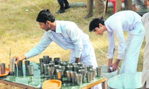 School students wash and fill glasses at a drinking water stall during the Shaheedi Diwas function in Kathua on Thursday.