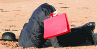 A protester from the Put People First action group puts his head in the sand as he poses for photographers during the G20 Finance Ministers meeting in St Andrews, Scotland.  Reuters