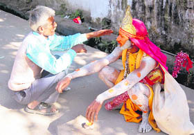 A mendicant dressed as Lord Hanuman chats with a passerby in Dehradun on Saturday. 