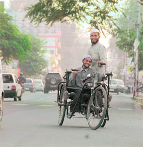 Two polio-stricken persons help each other in driving their tri-cycle in Dehradun on Sunday.